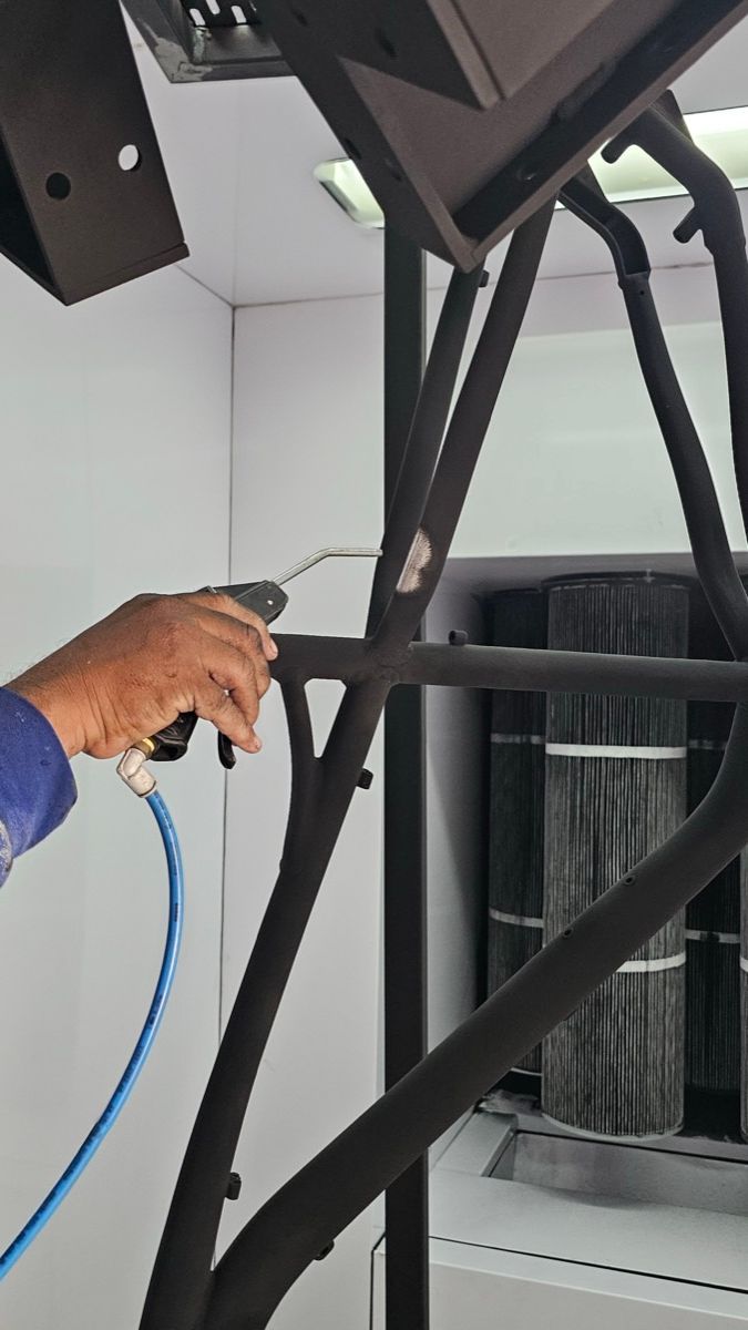 Aplicación de pintura electrostática sobre marco de acero en cabina de pintura de TESEY